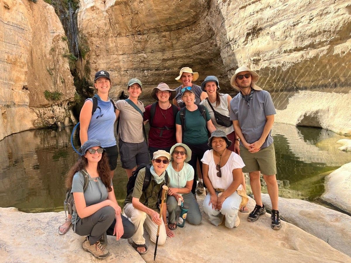 Field-study participants pose beside a pool beneath rocky canyon walls.