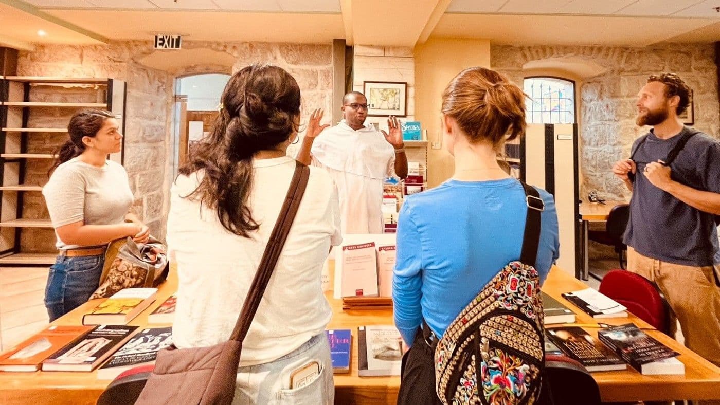JUC students listen to a guide among books and displays at the École Biblique.