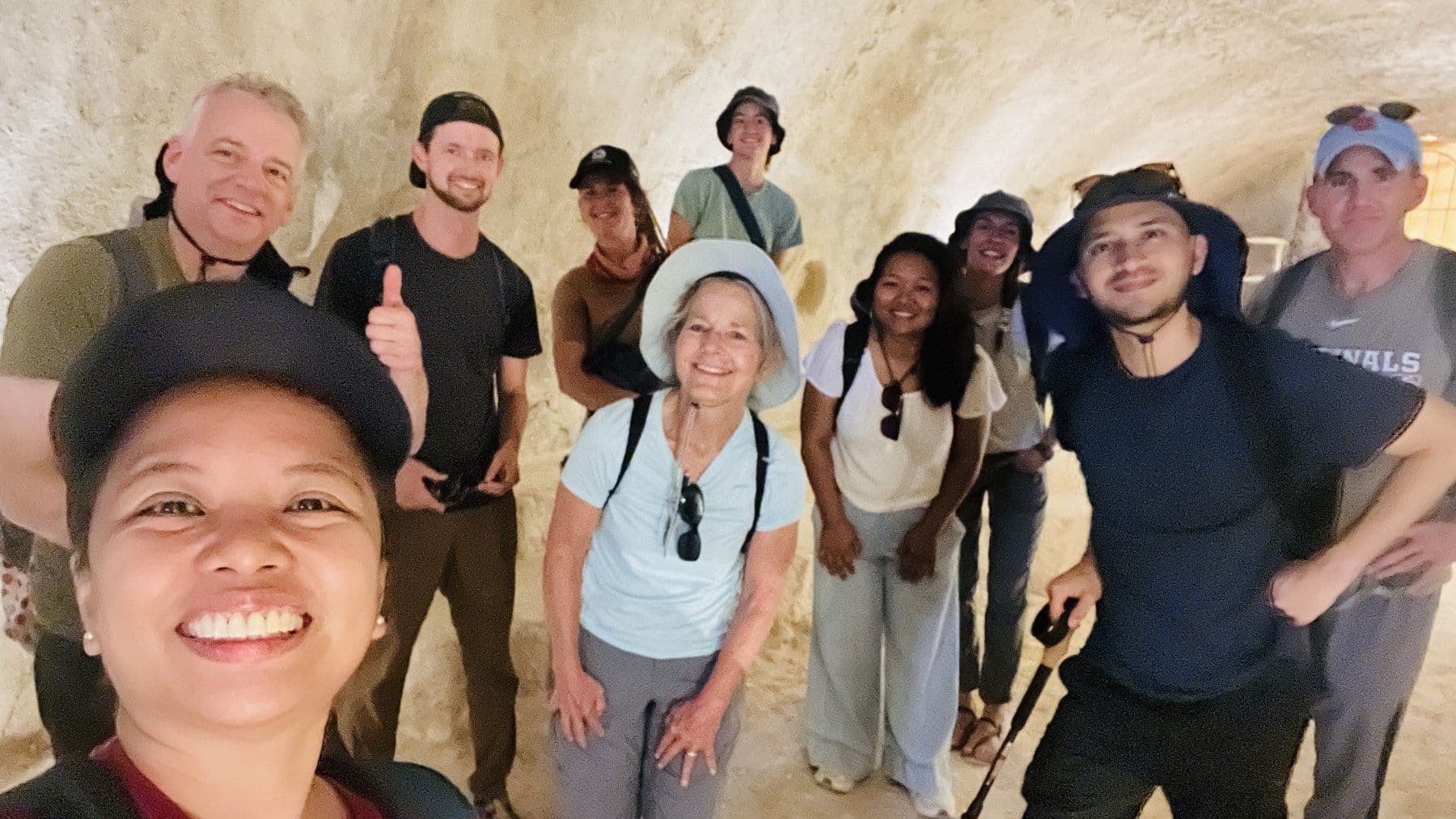 JUC students pose together inside a stone chamber during a field study.