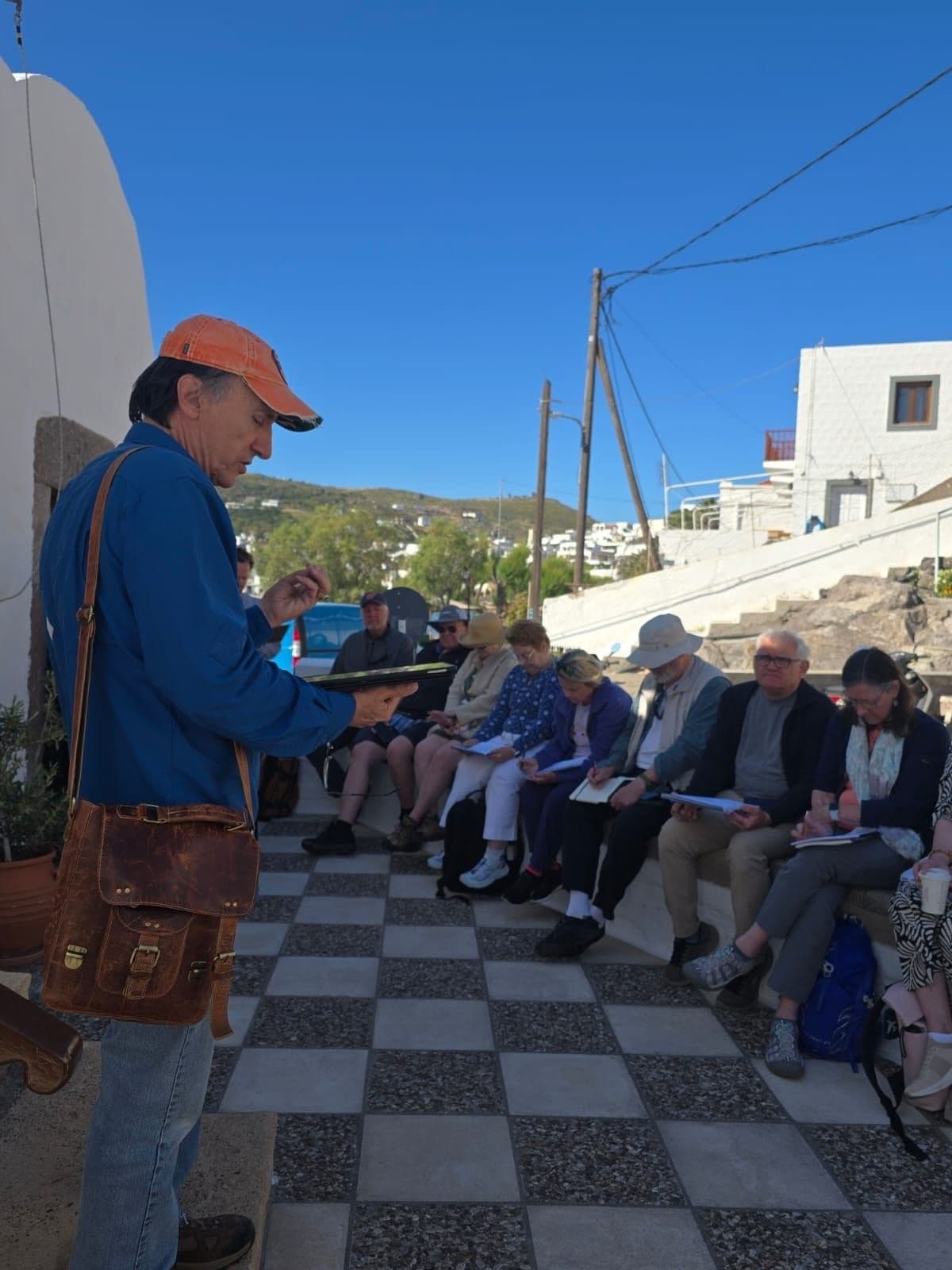 A field-study instructor addresses participants seated outdoors with open books and notebooks.