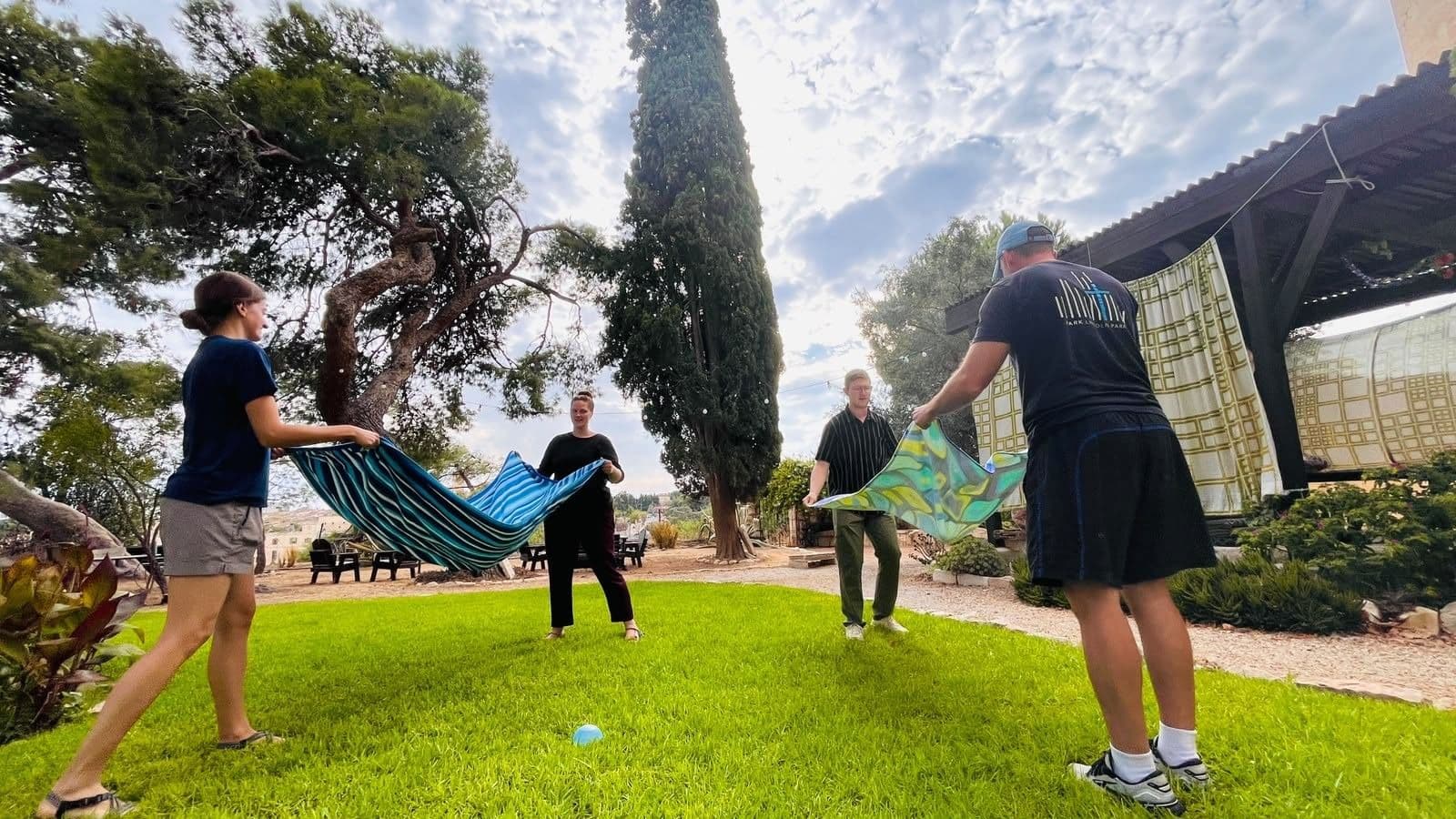 Community members play an outdoor game with towels on the campus lawn.