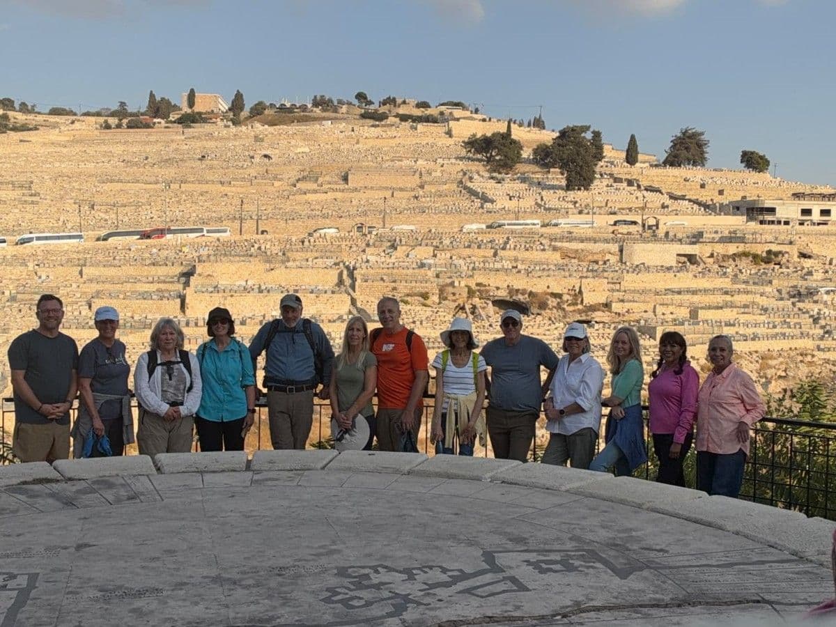 Pastor-Parishioner travelers pose together overlooking a terraced hillside in Jerusalem.