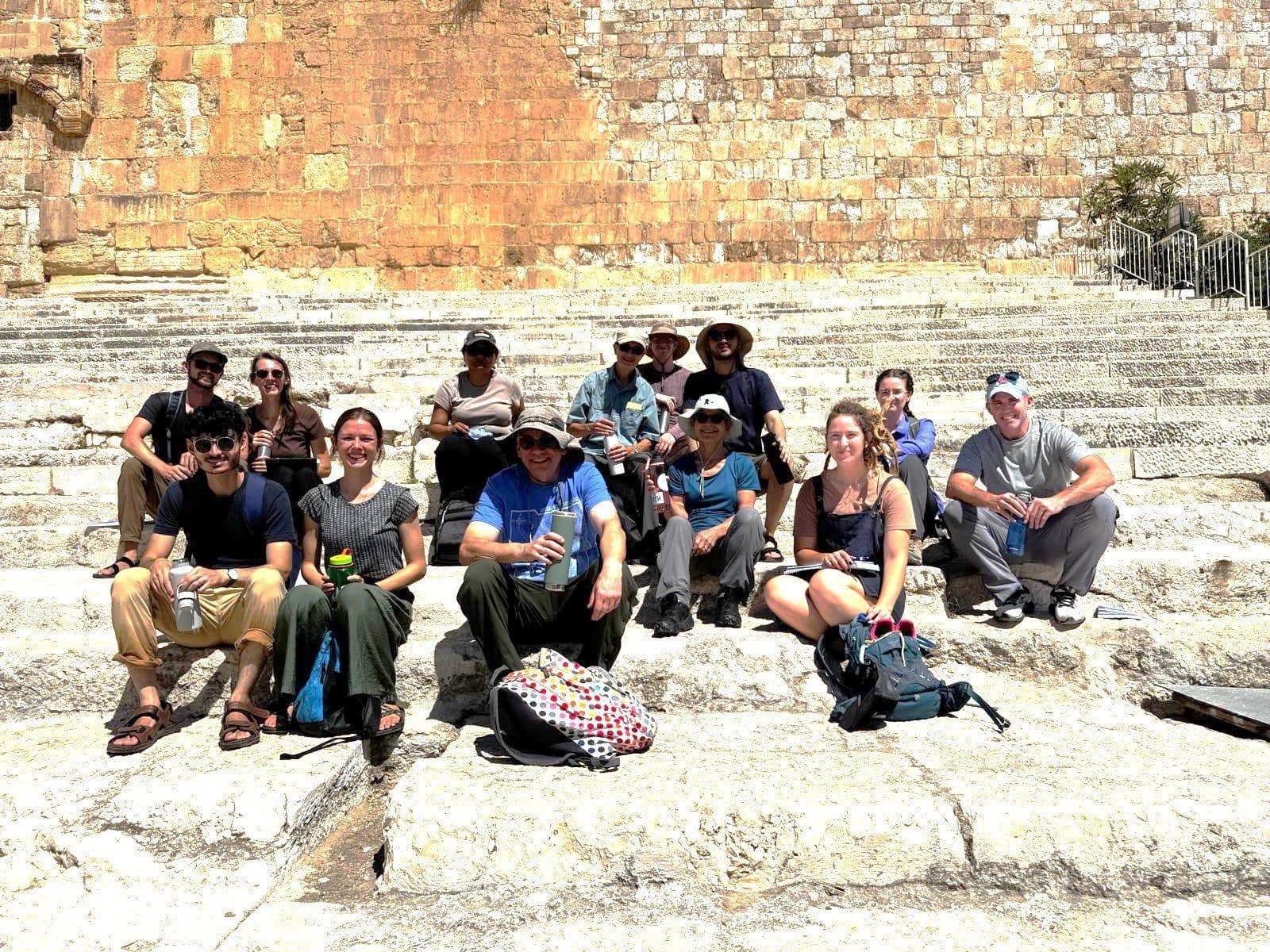 JUC students sit on ancient stone steps beside the Temple Mount.